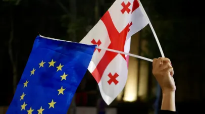 Person holding EU flag and Georgian flag in one hand above their head