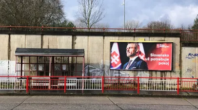 Bus shelter with a large Slovakian election billboard on the wall behind it 