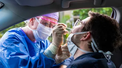 A doctor in a protective suit taking a nasal swab from a person to test for possible coronavirus infection