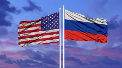 American and Russian flags side by side with pink and blue clouds in the backgrounds