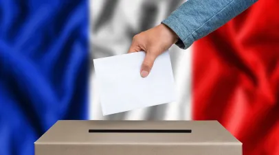 Woman dropping ballot into ballot box. French flag in the background