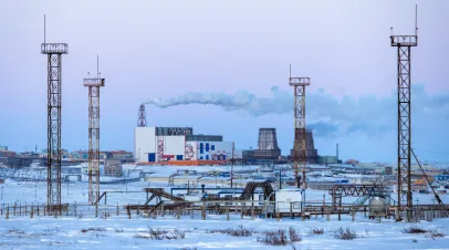 A view of the towers and structures of a gas-pumping station in the tundra and a large combined heat and power plant.