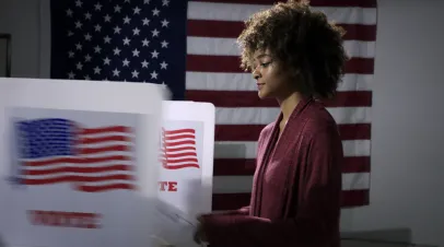 MS Young mixed-race woman ready to vote with blurred voting booth in foreground