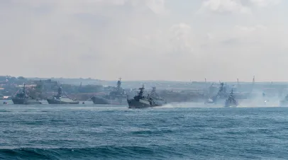 Russia, Sevastopol - July 21, 2021: Group of modern russian warships sails in Sevastopol bay during Russian Navy Day rehearsal in a sunny day next to anchored battle ships.