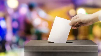 hand holding ballot paper for election vote concept on colorful background.
