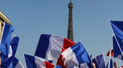 people waving French flags in front of Eiffel Tower