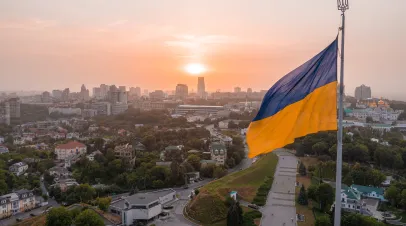 Aerial view of the Ukrainian flag waving in the wind against the city of Kyiv, Ukraine near the famous statue of Motherland at sunset.