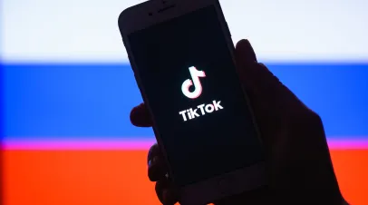 Tik Tok application on a smartphone against the background of the Russian flag.