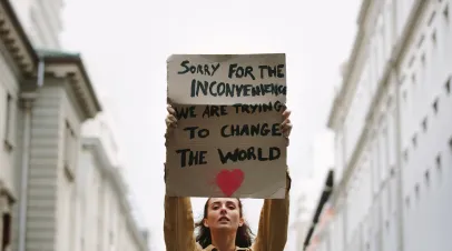 Young woman holding poster and protesting. Demonstrator making protest about climate change.