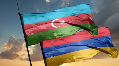 Flags of Azerbaijan and Armenia flying over a sunset sky