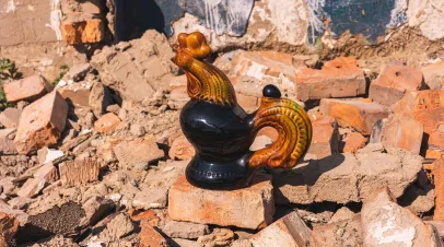 Picture of a rooster shaped teapot in the ruins of a bombed house