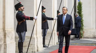 Mario Draghi walking down a passage flanked by uniformed Italian palace gaurds