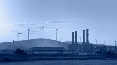 A factory with wind turbines in the background