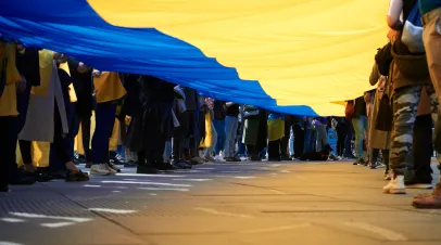 Crowd of people unfurling a large Ukrainian flag