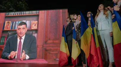 Presidential candidate George Simion is shown on a screen addressing his supporters