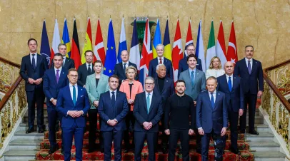 Group of European leaders standing on stairs in front of a row of flags