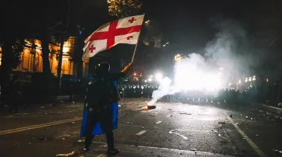 Man waving a Georgian flag confronting a large wave of protest police