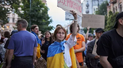 Young woman wearing a Ukrainian flag and holding a protest sign
