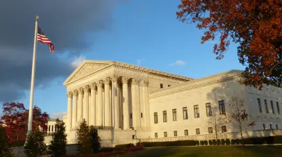 November 25, 2013, Washington, D.C, USA - U.S. Supreme Court Building in Washington, D.C., with American flag and autumn trees under dramatic sky.