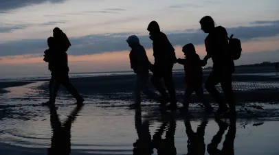 Migrants run across the beach at first light to board small boats that had come to collect them from further down the coastline on June 13, 2025 in Gravelines, France.