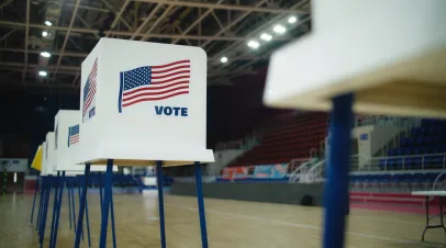 Elderly male voter with bulletin in hands comes to voting booth. Multicultural American citizens come to vote in polling station. Political races of US presidential candidates. National Election Day.
