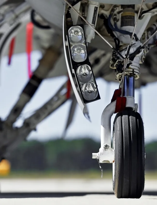 Military aircraft detail with landing gear and engine cover on a runway