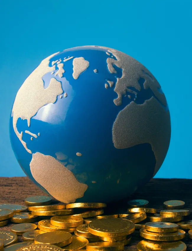 Pile of coins with a small globe sitting on it