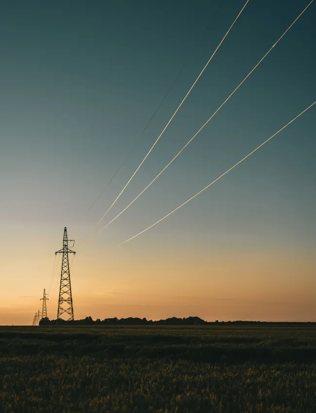 The silhouettes of transmission towers at sunset.