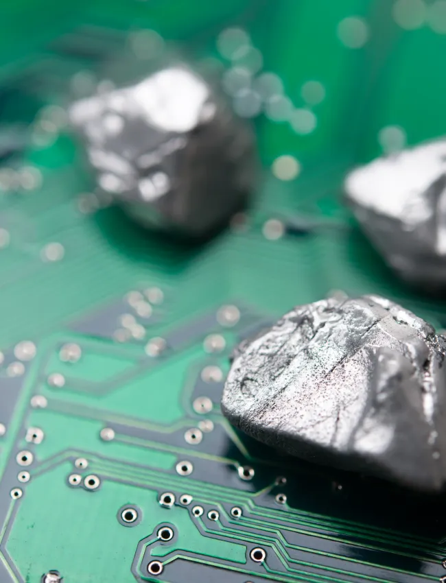 Mineral rare earth element on green electronic circuit board background copy space. US vs China chip war, tech war, semiconductor industry concept. China curbs on exports of rare earth element to US.