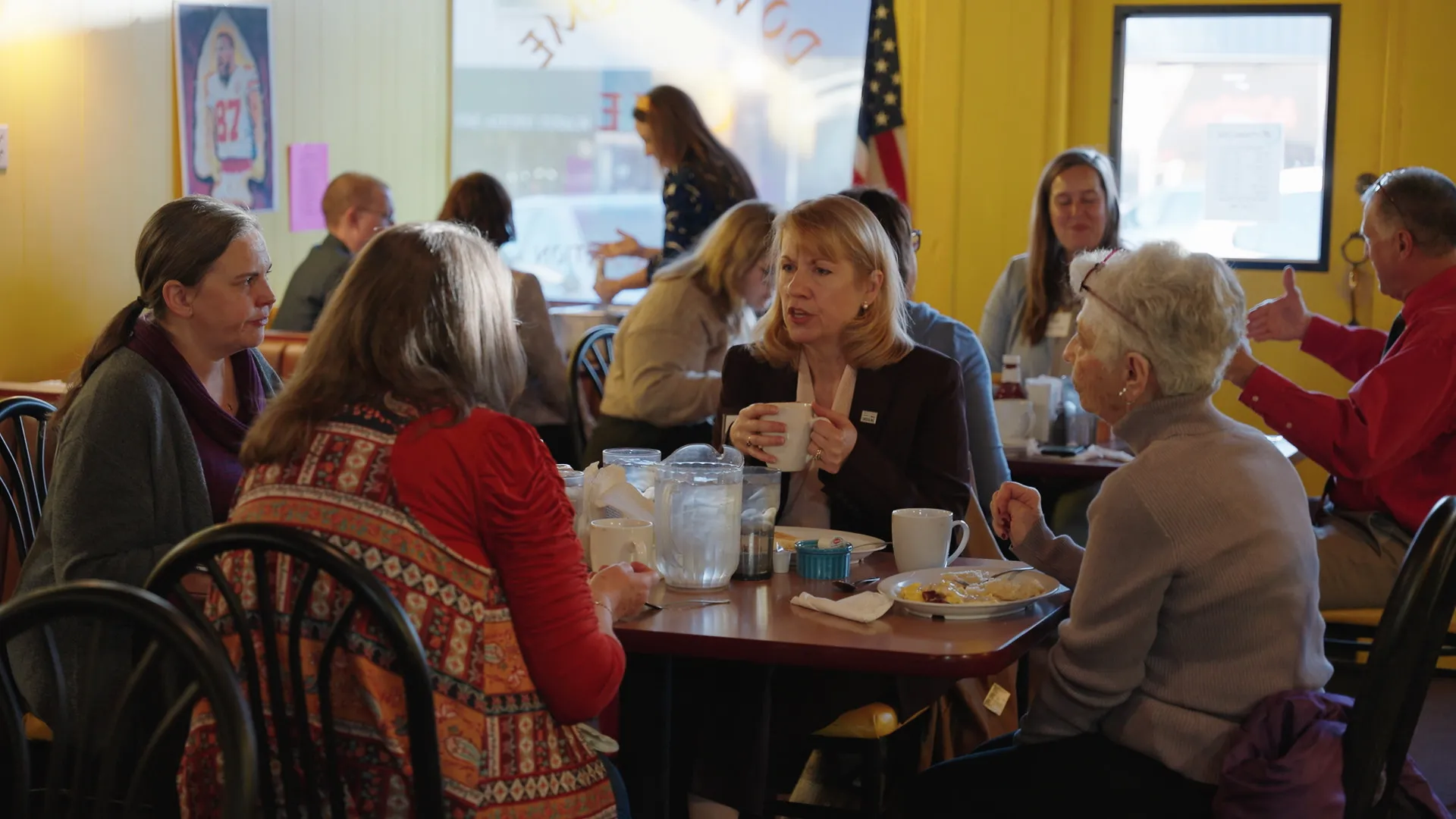 Group of people sitting around a diner table and speaking
