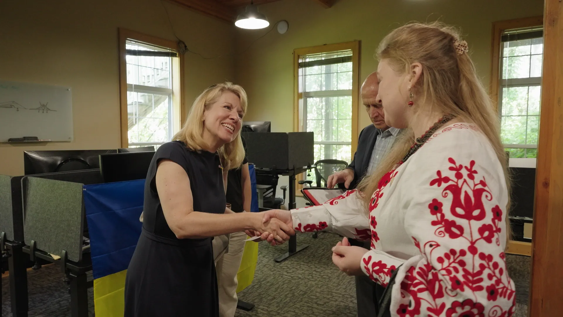 A woman with blonde hair shaking hands with another woman
